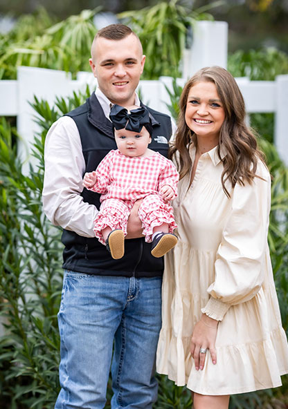 Ginger and Hayden Griffith are posing and holding their baby, Emerson.