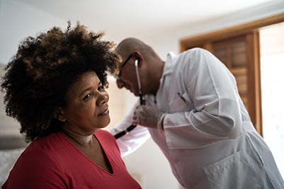 Doctor listening to a woman's heart beat.